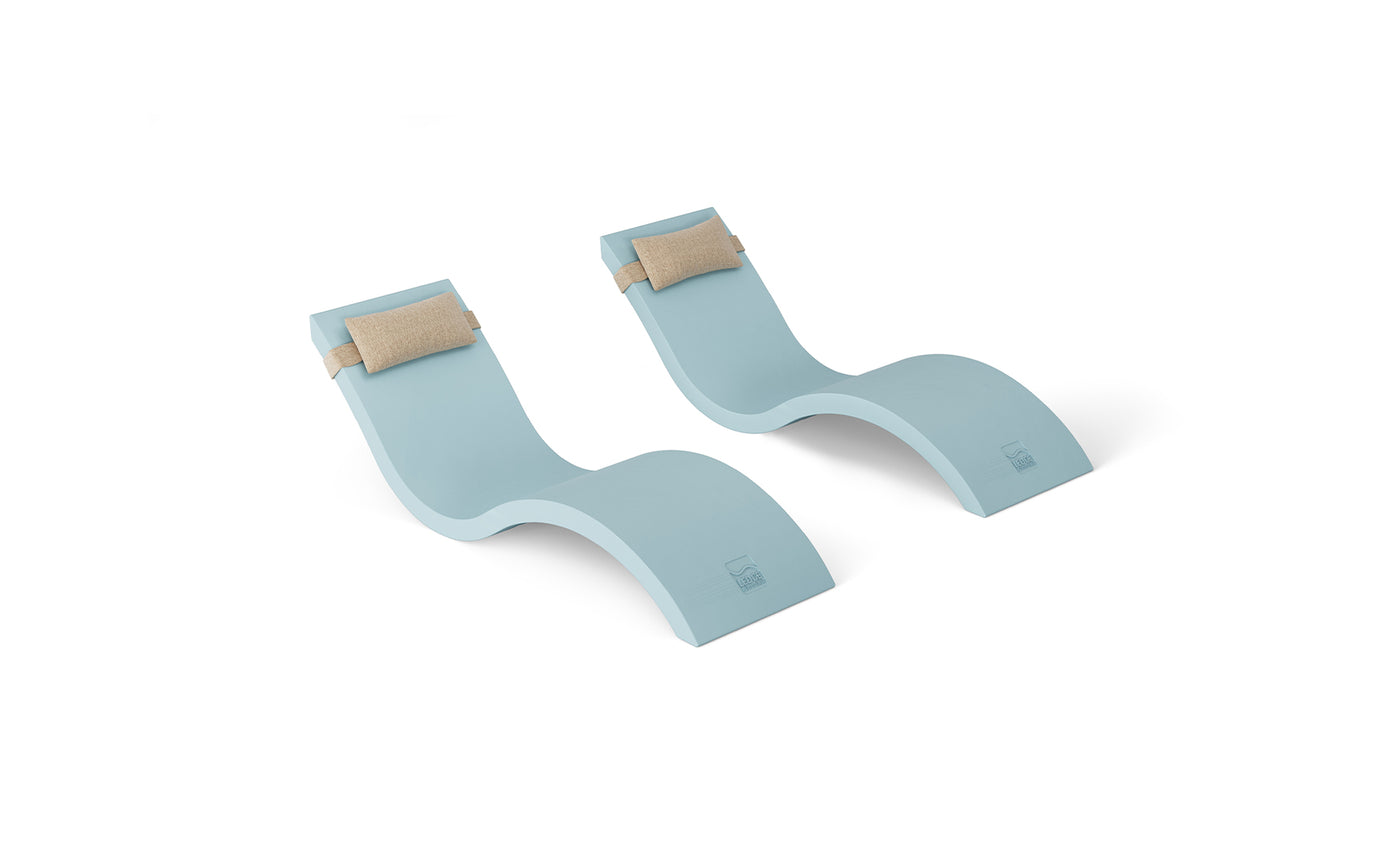 The Ledge Lounger Outdoor Escape In-Pool Furniture Bundle features two light blue, S-shaped chaise lounge chairs with beige headrest pillows, arranged side by side against a white background.