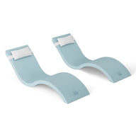 The Outdoor Escape In-Pool Furniture Bundle by Ledge Lounger features two modern, light blue chaise lounges with a wavy design, paired with white headrest pillows on a white background, offering a minimalist and stylish look perfect for any outdoor setting.
