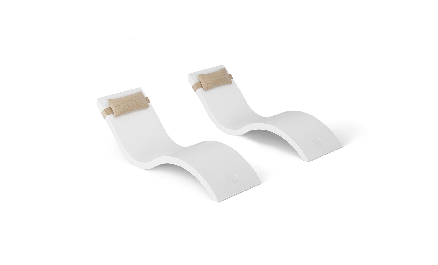 Two Ledge Lounger Outdoor Escape In-Pool Furniture chairs with smooth, curved designs are set against a plain white background, each featuring an attached beige cushion as a headrest pillow for added comfort.