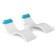 The Ledge Lounger Outdoor Paradise In-Pool Furniture Bundle includes two white, curved lounge chairs connected by a central cylindrical table. Each chair has a blue headrest and arches like gentle waves, making them ideal modern minimalist pool ledge furniture.