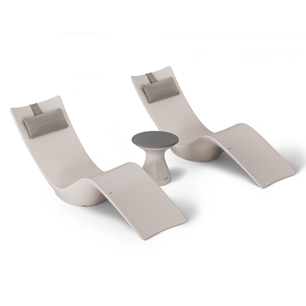Ledge Loungers Resort Luxury Outdoor Paradise In-Pool Furniture Bundle offers two modern, curved beige lounge chairs with gray headrests and a small, round gray table for poolside relaxation. The sleek, minimalist design complements a plain white backdrop.