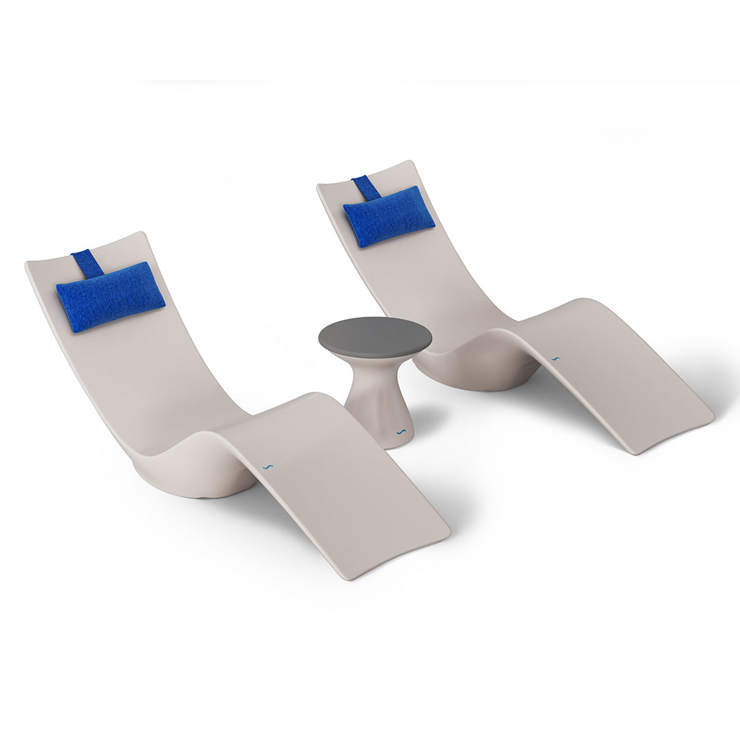 The Ledge Lounger Resort Luxury Outdoor Paradise In-Pool Furniture Bundle features two sleek beige chairs with blue headrests and a round gray table on a white background, perfect for poolside relaxation.