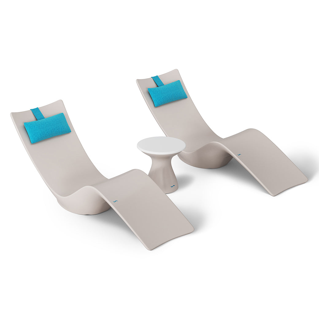 The Resort Luxury Outdoor Paradise In-Pool Furniture Bundle by Ledge Lounger features two modern beige lounge chairs with turquoise headrests and a small round white table, perfect for elegant relaxation poolside against a plain white background.