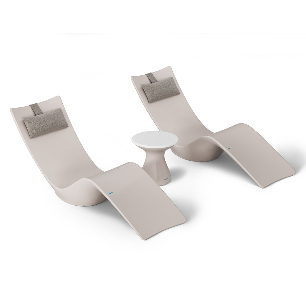 The Resort Luxury Outdoor Paradise In-Pool Furniture Bundle by Ledge Lounger features two beige lounge chairs with gray headrests, resembling chaise loungers. They flank a white side table against a plain backdrop, evoking poolside relaxation with simplicity and elegance.