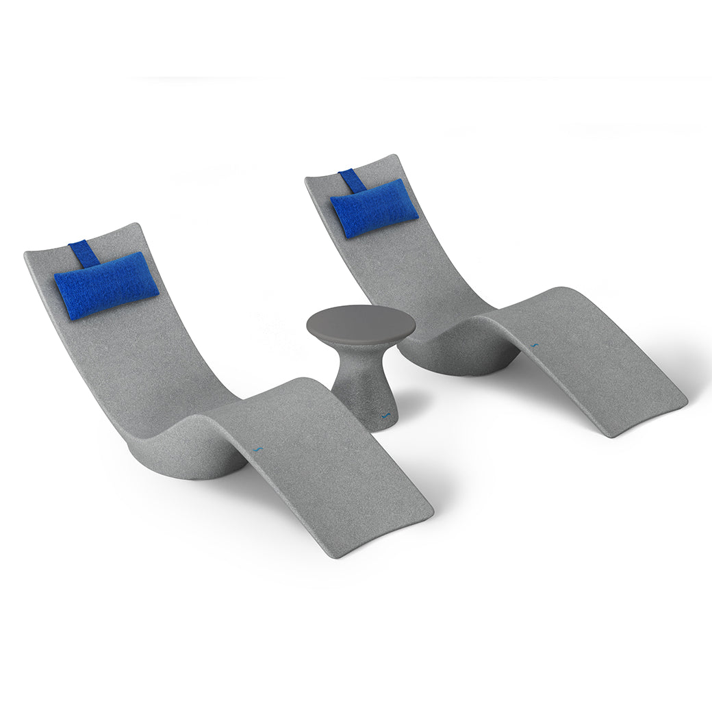 The Resort Luxury Outdoor Paradise In-Pool Furniture Bundle by Ledge Lounger features two modern gray curved chaise loungers with blue cushions, perfectly flanking a small round gray table, creating a stylish poolside look against a plain white backdrop.