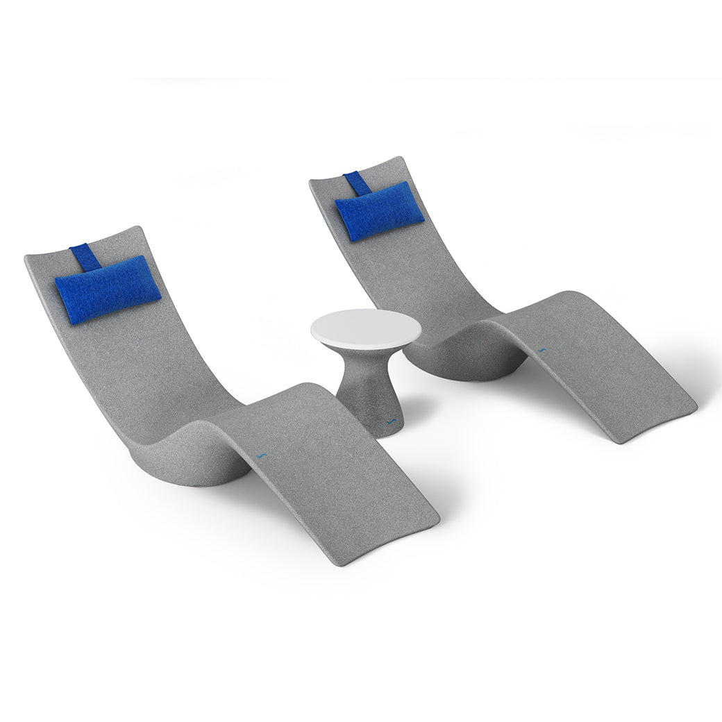 The Resort Luxury Outdoor Paradise In-Pool Furniture Bundle by Ledge Lounger includes two modern, curved gray chaise loungers with attached blue cushions flanking a small round white table, ideal for poolside relaxation against a plain white background.