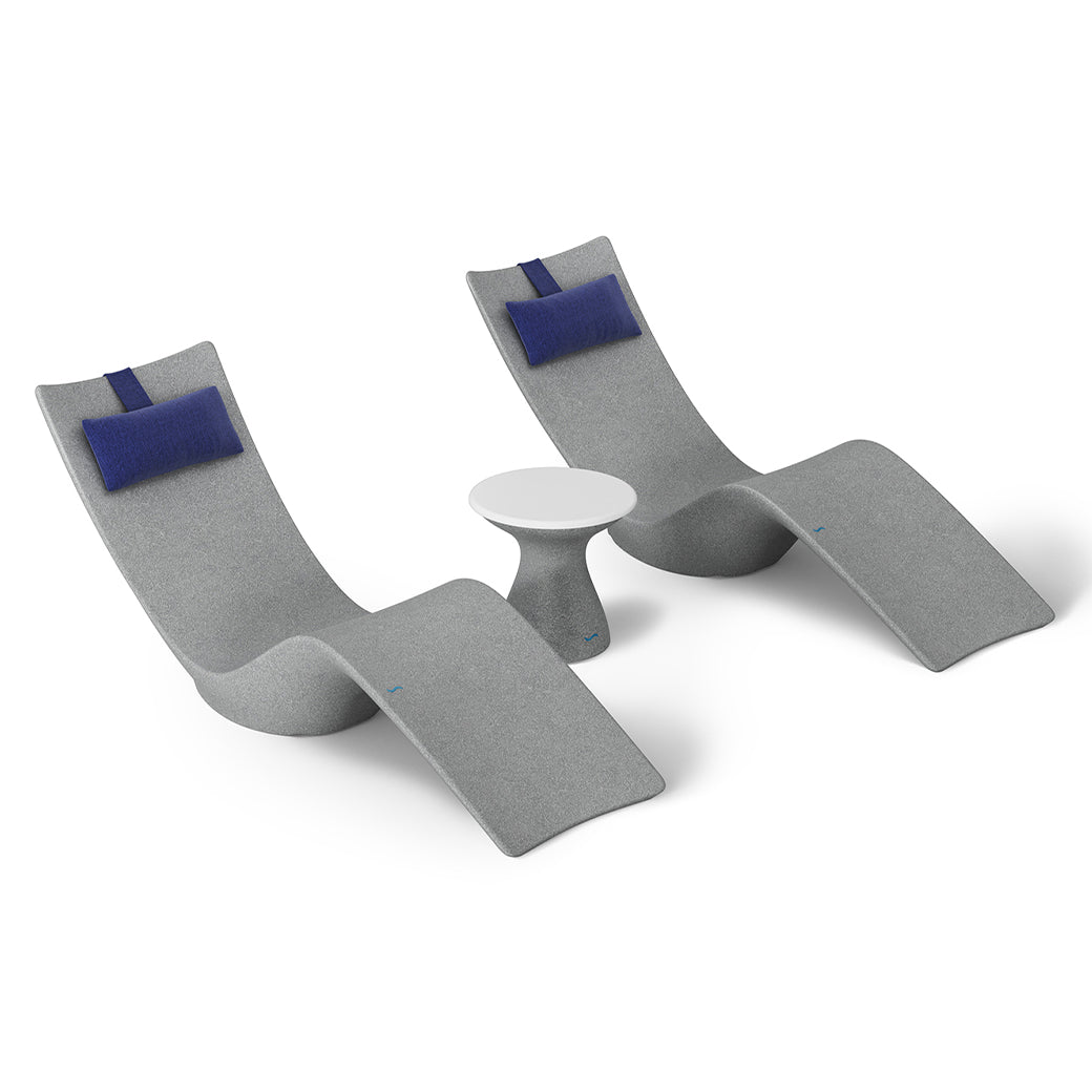 The Resort Luxury Outdoor Paradise In-Pool Furniture Bundle by Ledge Lounger features two sleek, curved gray lounge chairs with blue cushions flanking a small round white table, creating a minimalist and contemporary poolside setup perfect for any outdoor space.