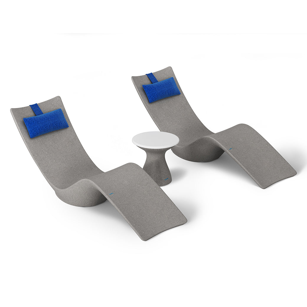 The Resort Luxury Outdoor Paradise In-Pool Furniture Bundle by Ledge Lounger features two sleek gray chaise loungers with blue headrests and a small round white table, ideal for poolside relaxation against a minimalist white backdrop.