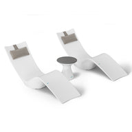 Two modern white chaise lounges with gray headrest cushions are symmetrically placed beside a small round table, ideal for poolside relaxation. The clean, minimalist design of the Resort Luxury Outdoor Paradise In-Pool Furniture Bundle by Ledge Lounger stands out against a plain white background.