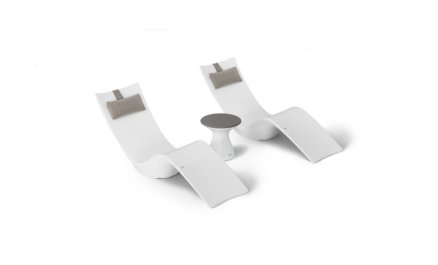 Two modern white chaise lounges with gray headrest cushions are symmetrically placed beside a small round table, ideal for poolside relaxation. The clean, minimalist design of the Resort Luxury Outdoor Paradise In-Pool Furniture Bundle by Ledge Lounger stands out against a plain white background.