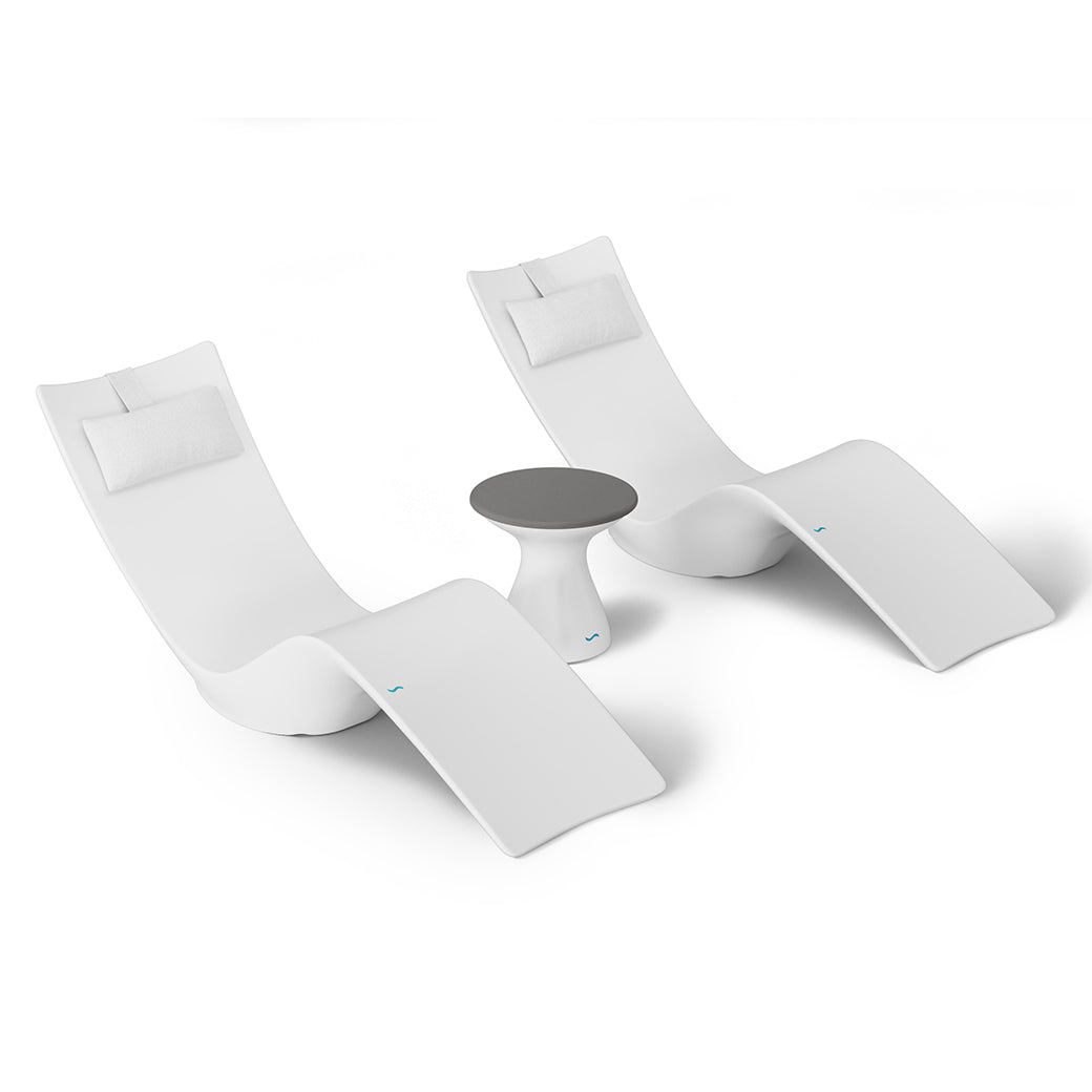 The Ledge Lounger Resort Luxury Outdoor Paradise In-Pool Furniture Bundle includes two modern white lounge chairs with headrests and a small round side table with a dark gray tabletop, ideal for poolside relaxation against a plain, minimalistic backdrop.