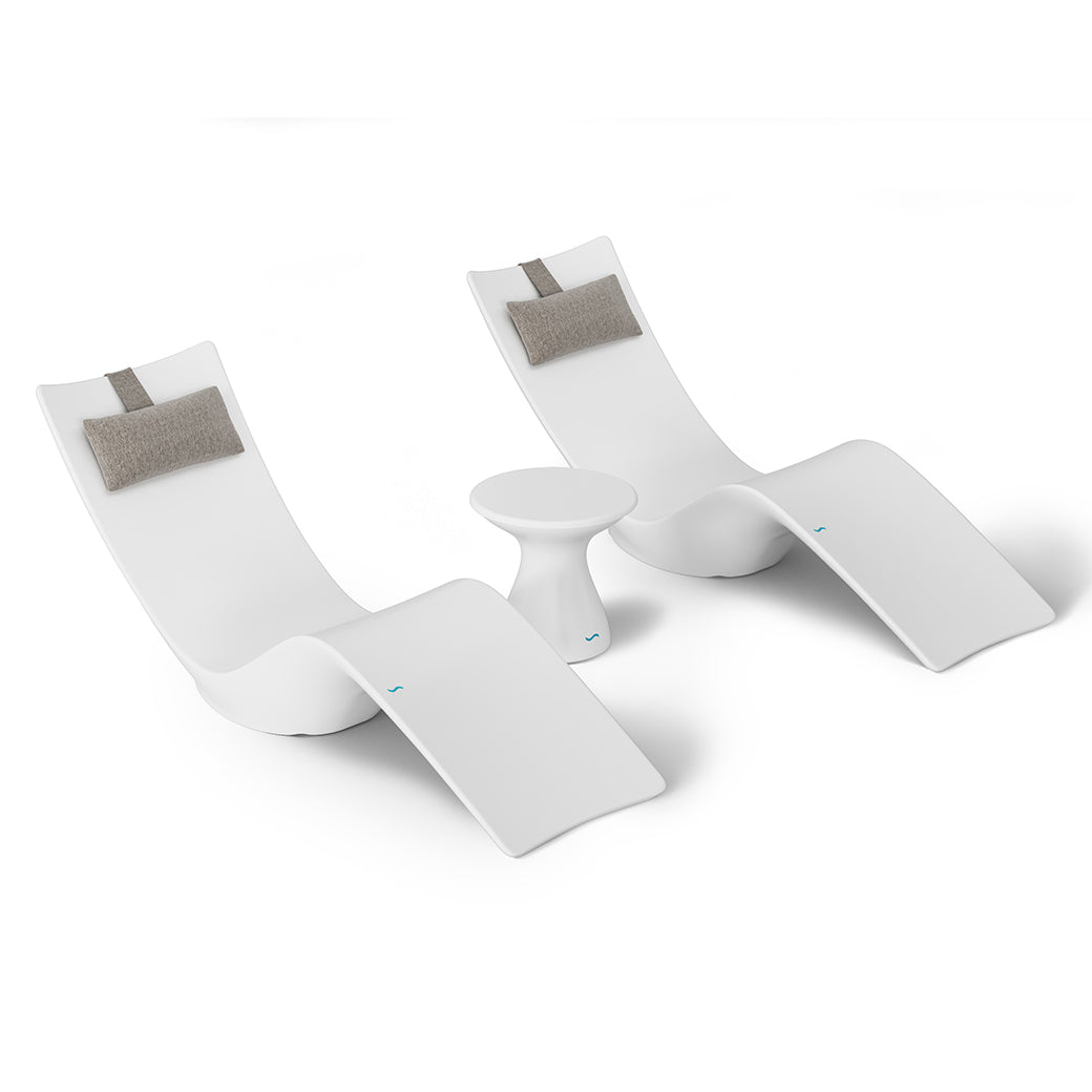The Resort Luxury Outdoor Paradise In-Pool Furniture Bundle by Ledge Lounger features two sleek white chaise loungers with gray headrests and a small round white table, ideal for poolside relaxation.
