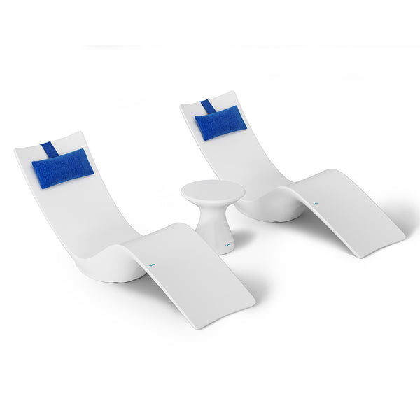 The Resort Luxury Outdoor Paradise In-Pool Furniture Bundle by Ledge Lounger features two modern white lounge chairs with blue head cushions flanking a small white table, ideal for poolside relaxation against a plain white backdrop to highlight its sleek and minimalist design.