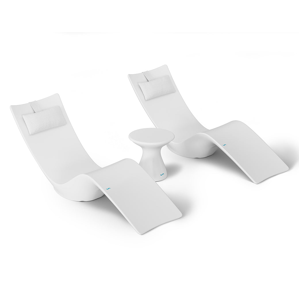 The Resort Luxury Outdoor Paradise In-Pool Furniture Bundle by Ledge Lounger features two modern white chaise loungers with headrests, spaced slightly apart. A small round white side table is centrally positioned, creating an ideal poolside relaxation spot against a plain white backdrop.
