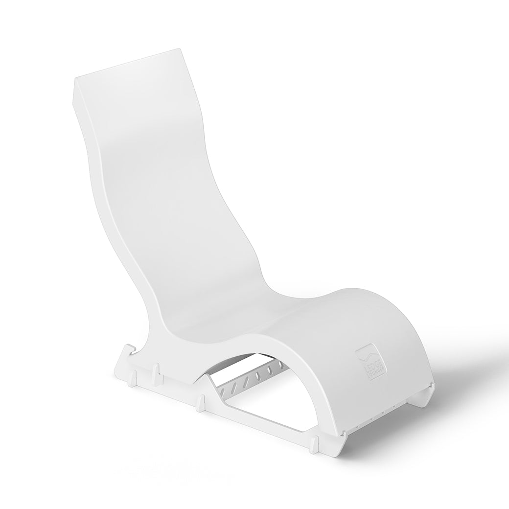 The Signature Chair Riser by Ledge Lounger is a modern, minimalist white lounge chair with a curved design. It has a smooth, wavy silhouette and sturdy base, making it ideal for outdoor relaxation or chic in-pool seating.