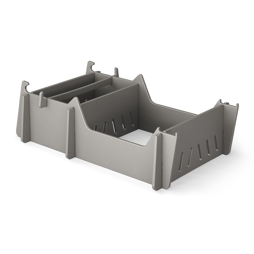 A gray, rectangular Signature Chair Riser by Ledge Lounger with vertical slits and pointed corner supports sits on a white background, ideal for organizing essentials during outdoor activities.