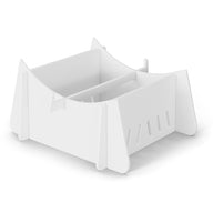 A white, minimalist desk organizer with an open-top design, central divider, and slotted side panels sits on the sleek Ledge Loungers Signature Chaise Riser against a plain white background.