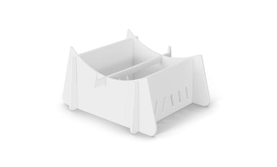 A white, minimalist desk organizer with an open-top design, central divider, and slotted side panels sits on the sleek Ledge Loungers Signature Chaise Riser against a plain white background.