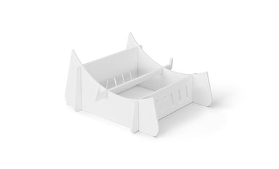 The Signature Chaise Riser by Ledge Lounger is a white minimalist book stand with two compartments, a curved base, and vertical slots. Its sleek modern design is perfect for organizing books upright against a plain white backdrop.