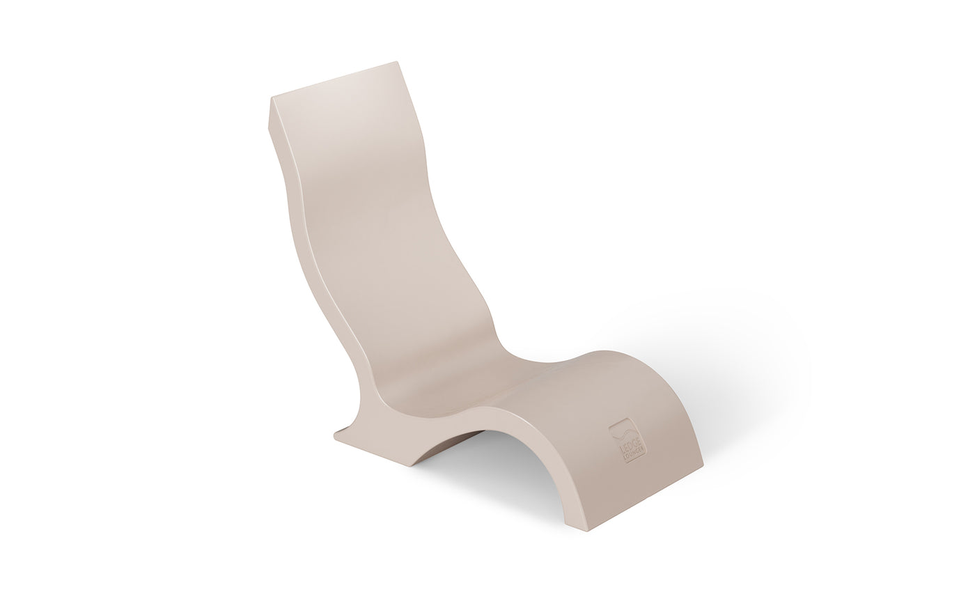 The Ledge Lounger Signature Chair With Short Riser is a modern beige lounge chair with a wavy ergonomic design and high backrest, perfect for stylish poolside seating, shown against a white background.