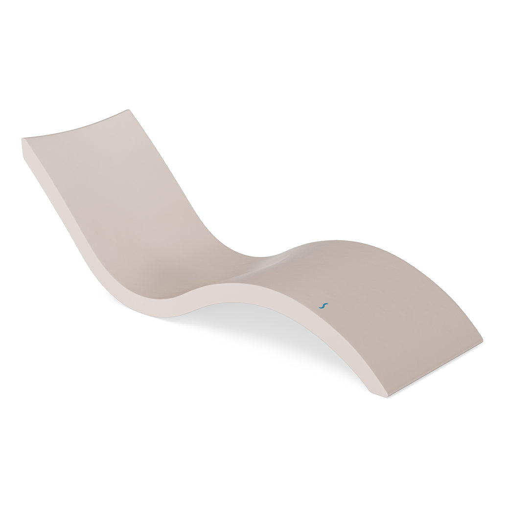 The Signature Chaise by Ledge Lounger features a modern, minimalist beige design with smooth curves that provide wave-like ergonomic comfort. Ideal for indoor or outdoor pool relaxation, it seamlessly blends style and functionality.