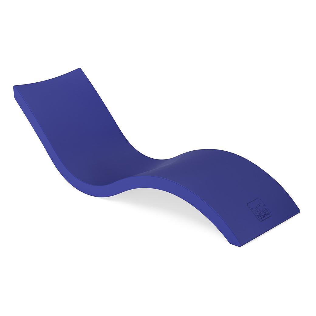 The Signature Chaise by Ledge Lounger is a sleek, modern deep blue lounger shown on a white background. It boasts an ergonomic design with a smooth, wavy form, elevated backrest, and contoured seat for ultimate pool relaxation.