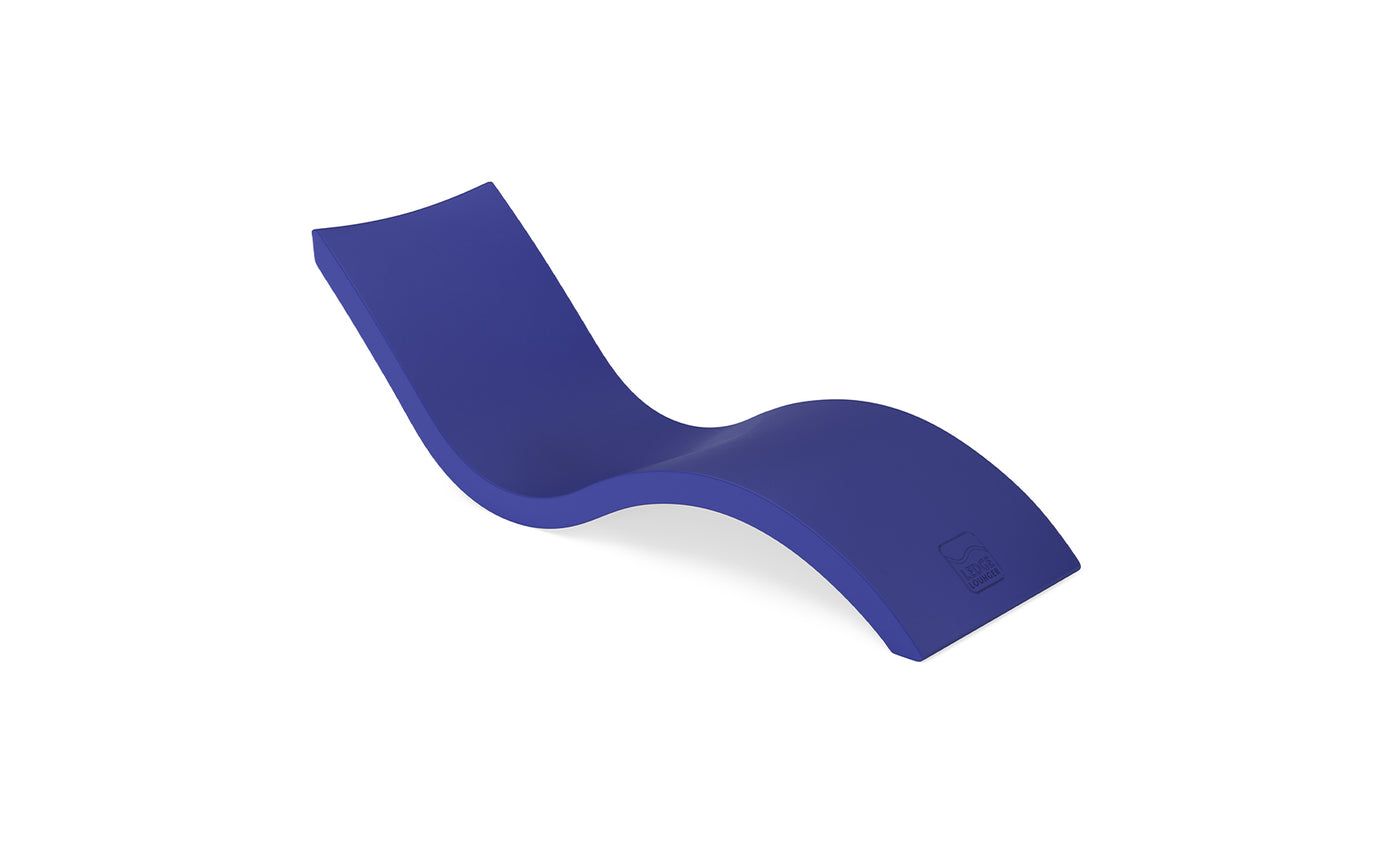 The Signature Chaise by Ledge Lounger is a sleek, modern deep blue lounger shown on a white background. It boasts an ergonomic design with a smooth, wavy form, elevated backrest, and contoured seat for ultimate pool relaxation.