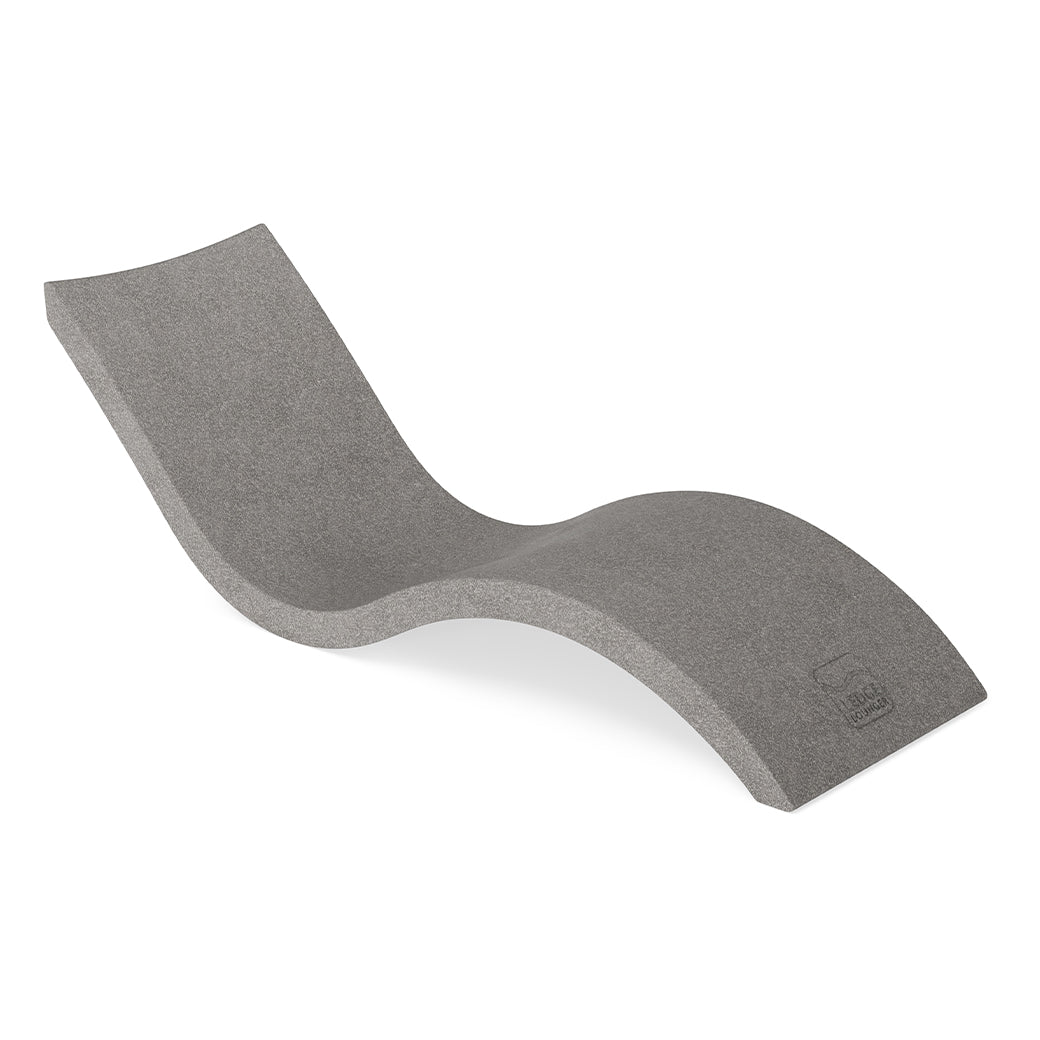 The Signature Chaise by Ledge Lounger is a modern, minimalist gray lounger featuring an ergonomic S-curve design and hidden legs, ideal for poolside relaxation, elegantly displayed on a plain white background.