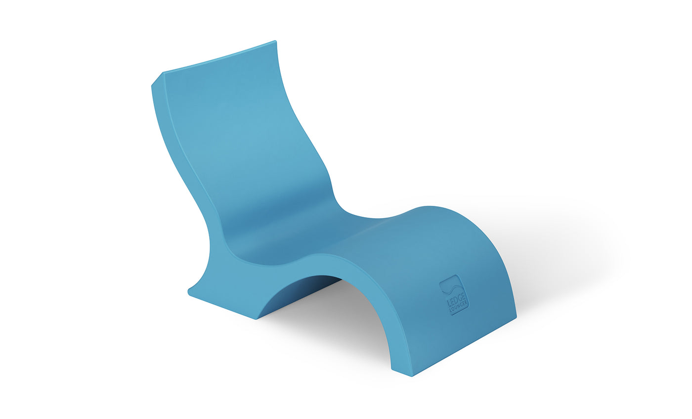 The Ledge Lounger Signature Lowback Chair With Short Riser is a modern blue curved plastic outdoor lounger with a wave-like design, ideal for poolside seating, shown on a plain white background.