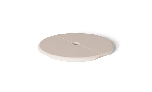 A beige, round ceramic saucer with a central hole and subtle grooves resembles the Ledge Loungers Signature Side Table Lid with Umbrella Hole. Displayed on a plain white background, it features a smooth surface and slightly raised edges, adding elegance to any poolside collection.