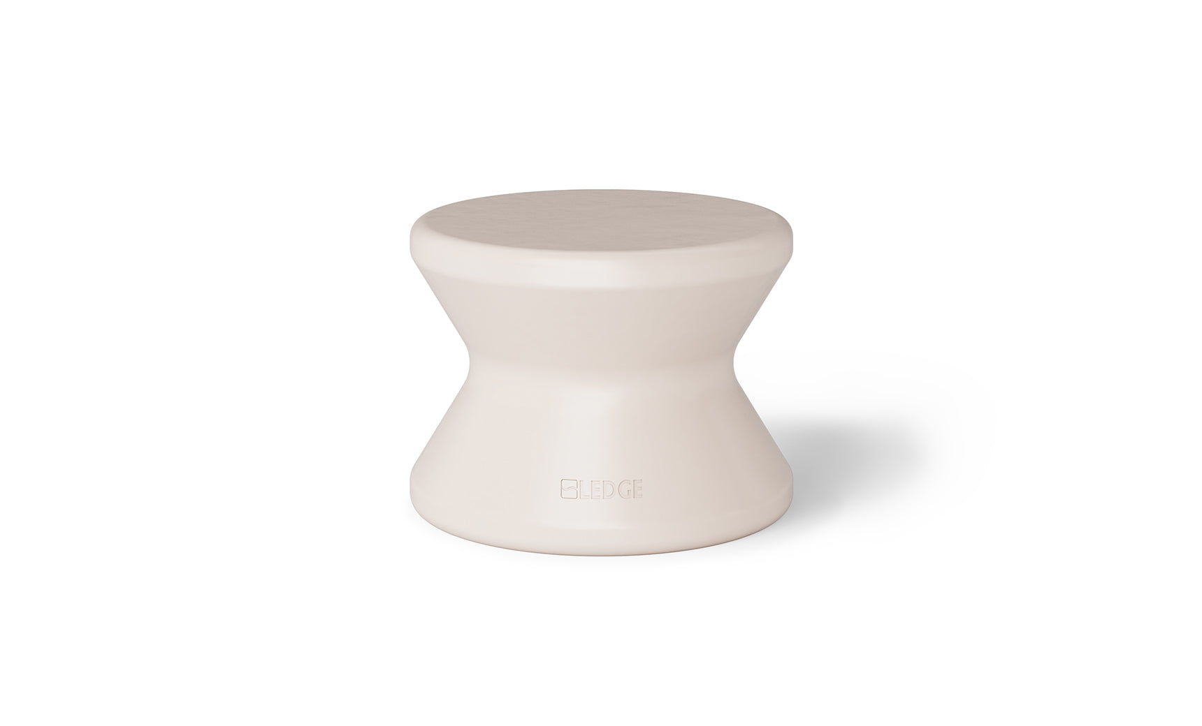 The Signature Standard Side Table by Ledge Lounger is a small, hourglass-shaped, light beige stool with a smooth surface for in-pool use on sun shelves. It features the word EDGE inscribed near the bottom, adding elegance and functionality.