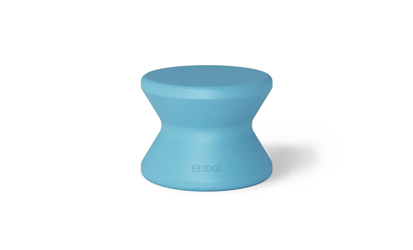 The Signature Standard Side Table by Ledge Lounger is a blue hourglass-shaped stool with a smooth finish, ideal for in-pool use. Its modern design features ELEDGE embossed near the base, making it perfect for a sun shelf.