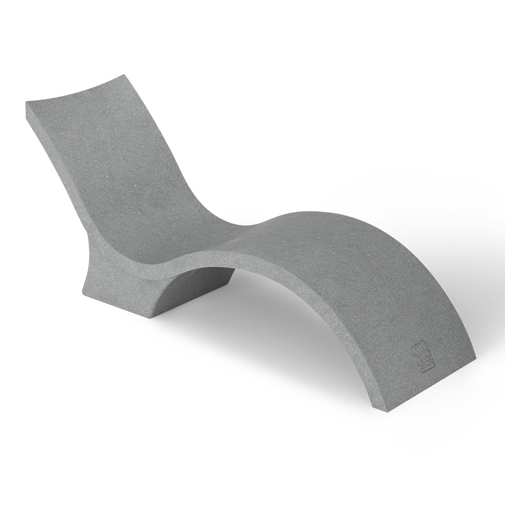 The Signature Chaise Deep by Ledge Lounger is a minimalist grey lounge chair with a wavy, modern design like a chaise lounge, featuring smooth surfaces and continuous curves for a sleek look. Its shown against a plain white background.