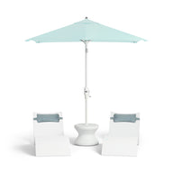 Two white lounge chairs with gray cushions surround a white round table under a 6.5 Square Signature 360° Tilt Umbrella from Ledge Lounger in light blue, featuring a rustproof frame for minimalist design and lasting outdoor relaxation.