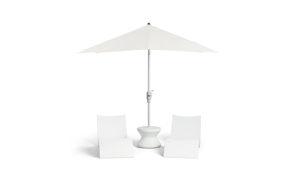 A sleek white patio setup includes two modern chairs, a Signature Standard Side Table by Ledge Lounger, and a large white umbrella. Its minimalist design is ideal for in-pool use on your sun shelf.