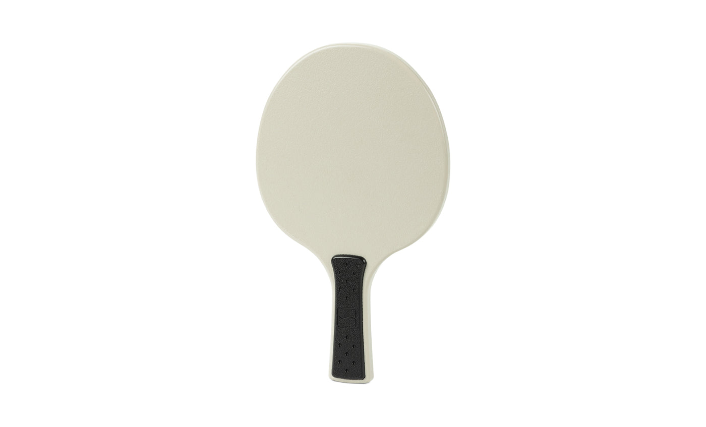 The Ledge Lounger Table Tennis Paddle features a simple oval beige face and a short black textured handle, displayed against a plain white background.