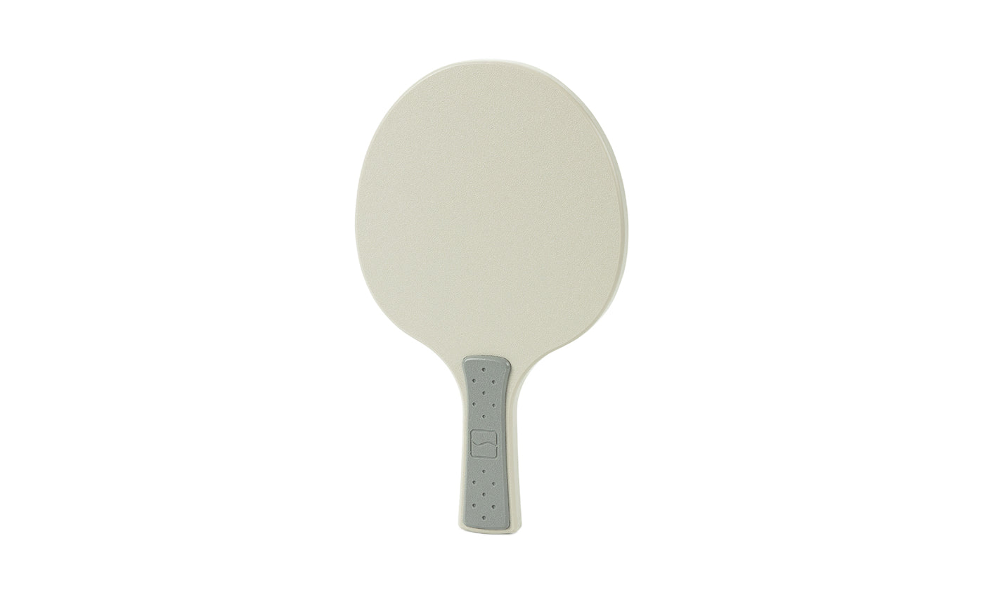 A beige Table Tennis Paddle by Ledge Lounger with an oval shape, light gray gripped handle, and dotted texture is displayed on a white background—perfect for any Ledge Table Tennis Set.