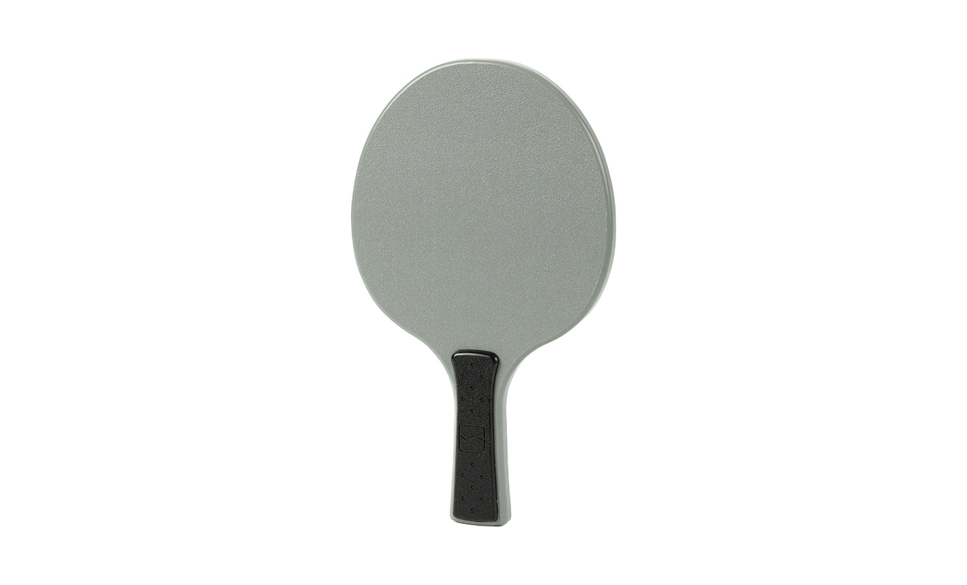 A gray Table Tennis Paddle by Ledge Lounger with a black handle is displayed on a white background.