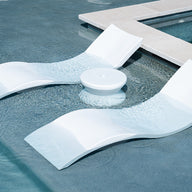 The Ledge Lounger Signature Chaise and Side Table In-Pool 6-Piece Set includes sleek white loungers and a round table, perfectly positioned in the shallow end as stylish pool ledge furniture next to a raised ledge.