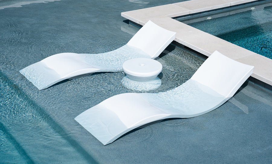 The Ledge Lounger Signature Chaise and Side Table In-Pool 6-Piece Set includes sleek white loungers and a round table, perfectly positioned in the shallow end as stylish pool ledge furniture next to a raised ledge.