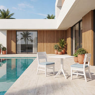 Modern house with large windows, a pool, and a patio area featuring a white table with Mainstay Dining Chairs topped with Ledge Lounger Mainstay Dining Side Chair Seat Cushions, all surrounded by potted plants and palm trees under a bright, clear sky.