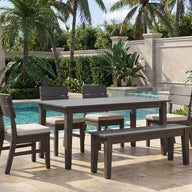 Experience the perfect blend of comfort and contemporary style with the Ledge Lounger Mainstay Dining 9-Piece Patio Set—a stunning sample product for your patio. This elegant arrangement includes four chairs and a bench, beautifully set on a stone patio beside the pool and framed by vibrant tropical plants and swaying palm trees. The Mainstay Dining Set offers a modern outdoor dining experience, ideal for relaxing al fresco gatherings.