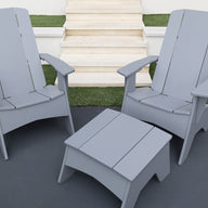 Two gray Ledge Lounger Mainstay Ultimate Adirondack chairs and a matching square table are set on a patio by white steps and artificial green grass.