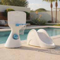 The Ledge Lounger Hoopstr and Signature Slide In-Pool Games Set are placed beside a modern outdoor pool with in-pool furniture, lounge chairs, and lush greenery, making for a fun and stylish setting on a sunny day.