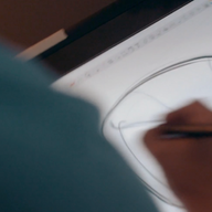A person uses a stylus on a digital tablet to sketch a large circle with intersecting lines, focusing on their hand and the drawing. The product involved is Test Product for Transaction Test by Ledge Lounger, set against a blurred background.