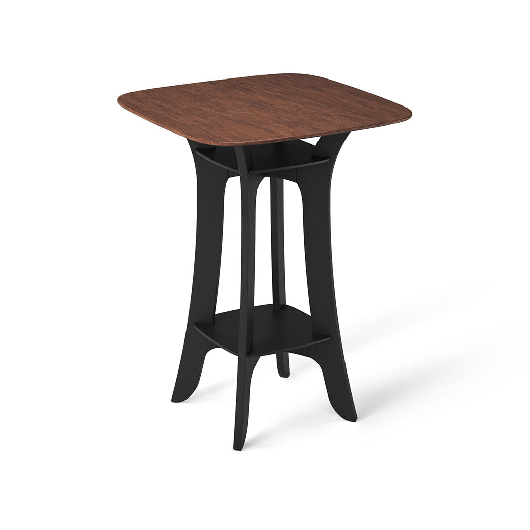 The Haven Hightop Table by Ledge Lounger is a modern, square piece featuring a dark wood top and black curved legs for ergonomic comfort. Its durable design includes a matching lower shelf, making it sleek and contemporary—ideal for any stylish patio collection.