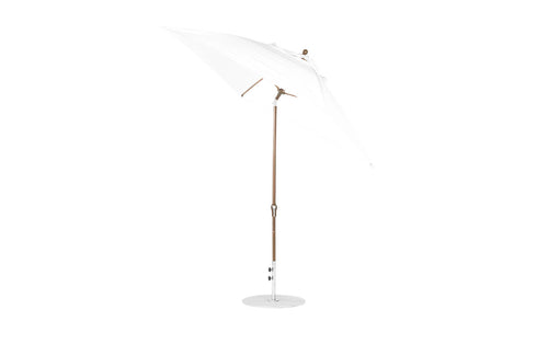 The Essential Fiberglass Umbrella - 7.5 Octagon Crank Auto Tilt by Ledge Lounger, showcasing marine-grade fabrics and wind resistance, features a wooden pole and circular base, standing slightly tilted to the right against a plain white background.