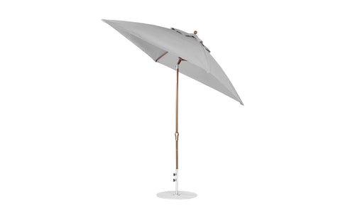 The Ledge Lounger Essential Fiberglass Umbrella features a 7.5 octagon design with a light gray canopy, wooden pole, and white circular base. Its wind resistant, includes an auto tilt crank mechanism, and offers marine-grade fabrics for a sleek garden or patio look.