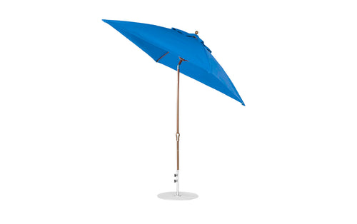 The Ledge Lounger Essential Fiberglass Umbrella, a 7.5 octagon with a crank auto tilt, features a blue canopy on a wooden pole with silver base set against a white background. Its marine-grade fabrics are taut for enhanced wind resistance and durability.