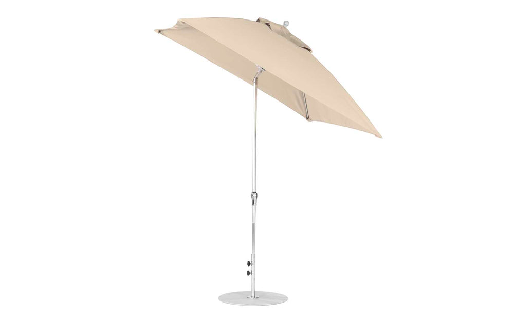The Ledge Lounger Essential Fiberglass Umbrella features a beige, marine-grade fabric square canopy and a tilting mechanism on a silver, corrosion-resistant metal pole. It stands on a round base, offering durability and ease of use with its 7.5 crank auto tilt feature.